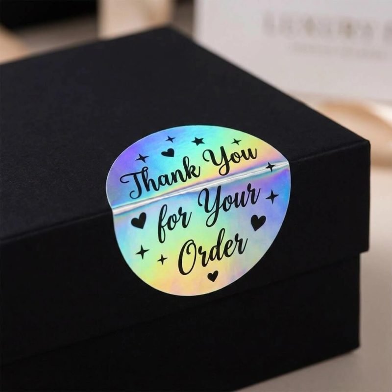 A custom die-cut holographic sticker showing a rainbow iridescent effect on a black package.