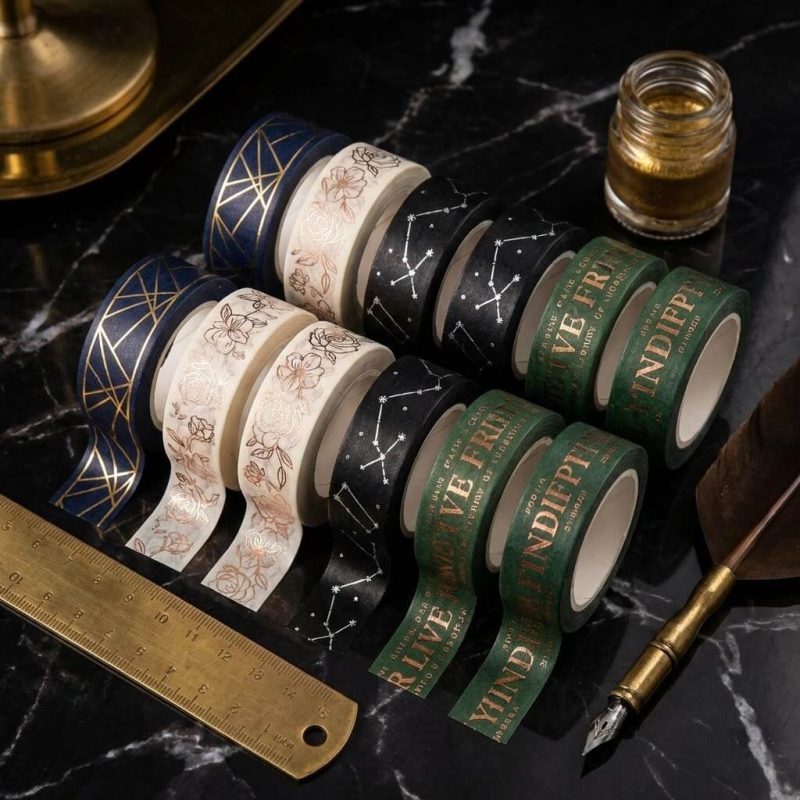 Several rolls of custom washi tape with various colorful floral and geometric patterns stacked on a wooden desk.