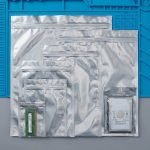 A translucent silver esd shielding bag containing a green computer motherboard (PCB).