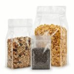 A high-clarity clear flat bottom bag filled with organic granola standing upright on a retail shelf.