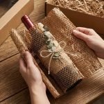 A roll of brown honeycomb wrap being stretched out to wrap a fragile glass vase.