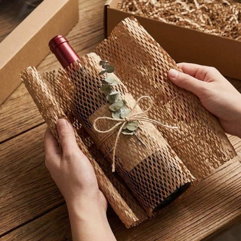 A roll of brown honeycomb wrap being stretched out to wrap a fragile glass vase.