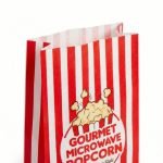 A microwavable popcorn bag showing the internal susceptor patch and freshly popped popcorn coming out.