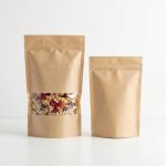 A brown kraft paper stand up pouch with window filled with granola and sealed with a zipper.