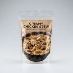 A microwaveable self-vent pouch filled with hearty beef stew, standing upright in a microwave with steam being released safely.