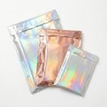 A shimmering holographic poly mailer reflecting a rainbow of colors with a boutique logo printed on it.