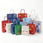 A group of Christmas paper bags in various sizes with reindeer and snowflake prints and red ribbon handles.