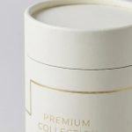A collection of round luxury paper tube boxes with gold foil logos for candle and tea packaging.
