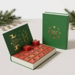 A large book-shaped advent calendar box in festive red and gold with 24 small drawers pulled open to reveal beauty gifts.